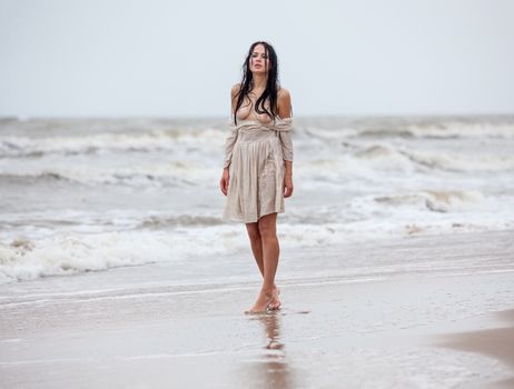 Beautiful young seminude woman in the cold sea waves