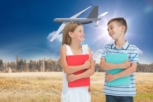 Smiling brother and sister holding their exercise books against large city on the horizon