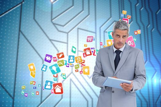 Serious businessman using tablet pc looking at camera against circuit board on futuristic background