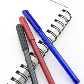 black red and blue pen with notebook isolated on white background