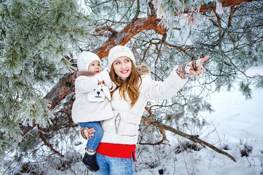 Attractive young mother holds daughter on hands and shows the side