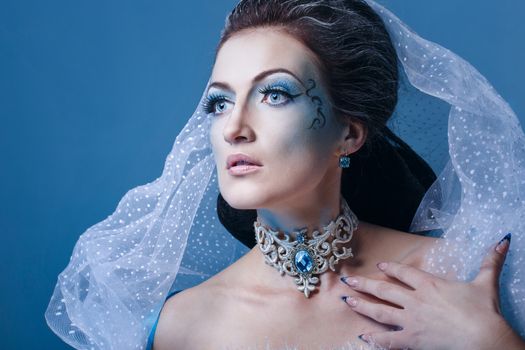 Attractive young girl with a theatrical makeup on the face in the image fabulous snow queen