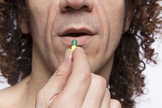 Cropped portrait of mediterranean looking man taking medicine pill