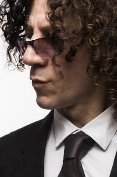 Cropped portrait of mediterranean looking man with curly hair wearing business suit and sun glasses