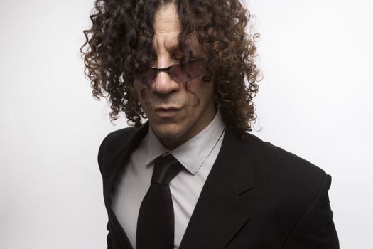 Cropped portrait of mediterranean looking man with curly hair wearing business suit and sun glasses