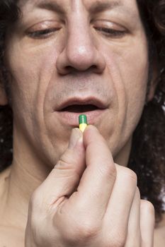 Cropped portrait of mediterranean looking man taking medicine pill