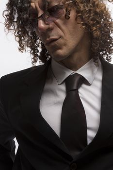 Cropped portrait of mediterranean looking man with curly hair wearing business suit and sun glasses