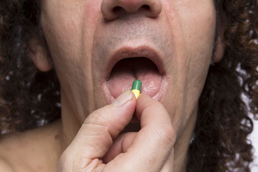 Cropped portrait of mediterranean looking man taking medicine pill
