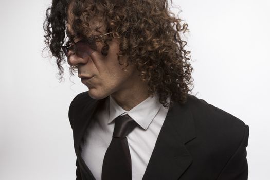 Cropped portrait of mediterranean looking man with curly hair wearing business suit and sun glasses