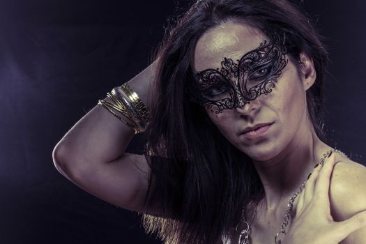 Beautiful young woman in mysterious black Venetian mask. Fashion photo. tribal design.