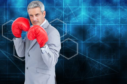 Tough businessman with boxing gloves against abstract technology background