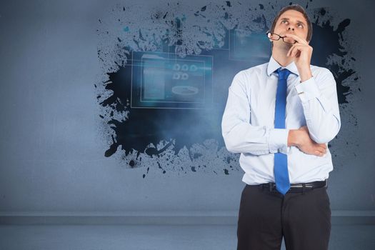 Thinking businessman biting glasses against splash showing technology interface