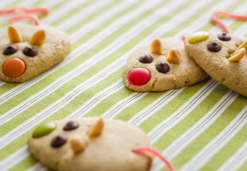 Cookies with mouse shaped and red licorice tail over green striped tablecloth