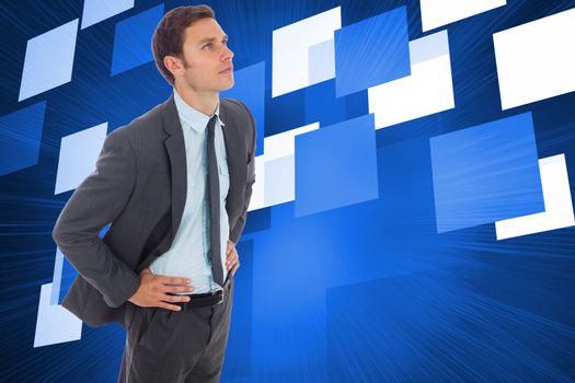 Serious businessman standing with hands on hips against abstract technology background