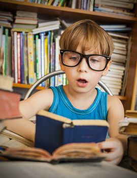 Close-up of cute boy reading book while preparing for lesson in library