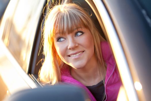 Beautiful smiling blonde woman rides a car