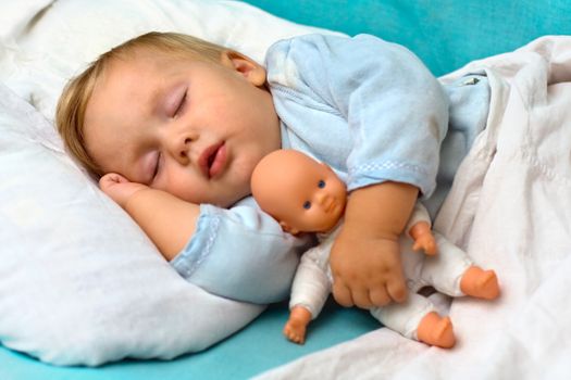 Portrait of toddler child,  sleeping in a bed with a toy doll