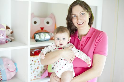 Mother with her dauther in a playroom with toys background