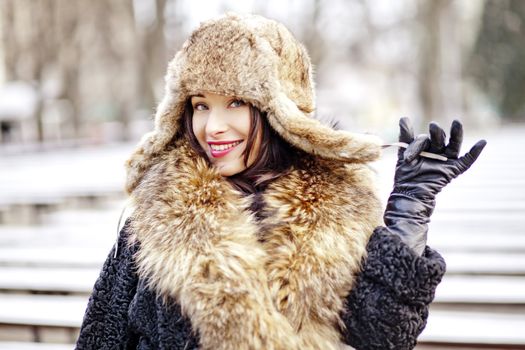 Happy woman in winter wearing real fur fashion clothes