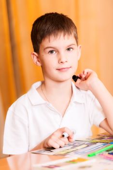 Boy colouring book looking at camera