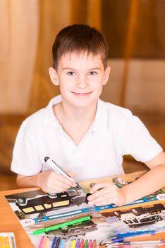 Boy colouring book looking at camera smiling