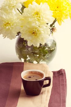 black coffee near the yellow flowers of chrysanthemums