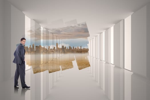 Serious businessman with hands on hips against abstract screen in room showing cityscape