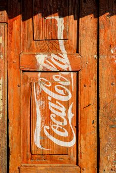 KATHMANDU, NEPAL - CIRCA JANUARY 2014: Vintage Coca-Cola adverisement painted on a red wooden door.