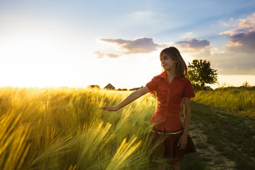 Teenage girl in wheat field likes a crop