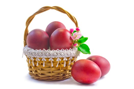 Three Easter eggs, painted in red, are beautifully decorated with wicker basket. Presented on a white background.