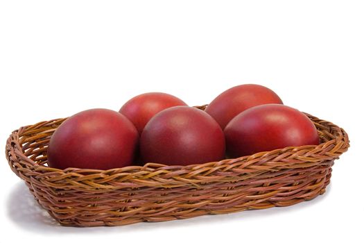 Three Easter eggs, painted in red, are beautifully decorated with wicker basket. Presented on a white background.