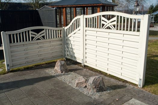 Decorative white wooden fence in a beautiful backyard garden