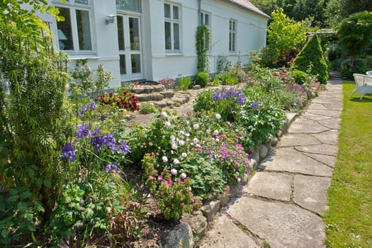 Beautiful delightful flower beds in front of a house English garden                               