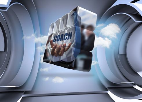 Businessman holding coach text on abstract screen against clouds in a futuristic structure