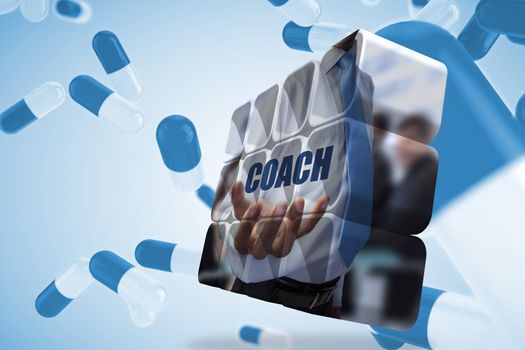 Businessman holding coach text on abstract screen against blue pills floating