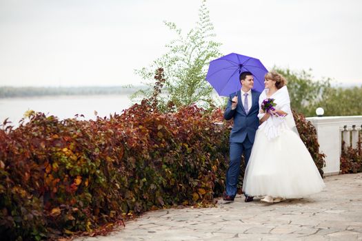 bride and groom walking under umbrella