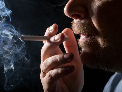 Portrait man smoking cigarette, closeup on black background