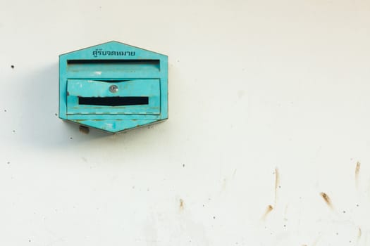 the green mailbox is located on a dirty wall.
