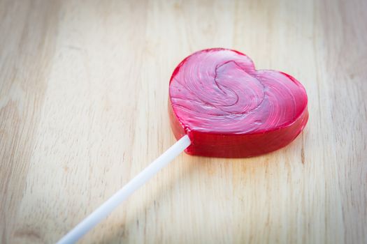 Heart shaped colorful lollipop on wooden background