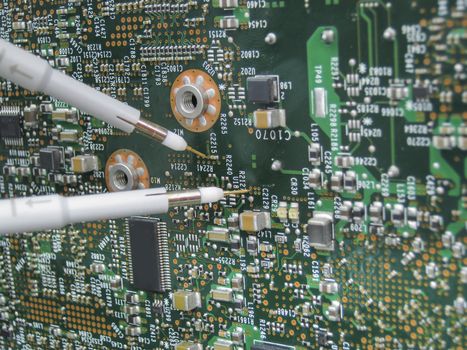 Multimeter probes examining a PCB circuit board