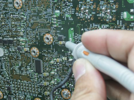 Multimeter probes examining a PCB circuit board