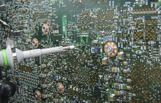 Multimeter probes examining a PCB circuit board