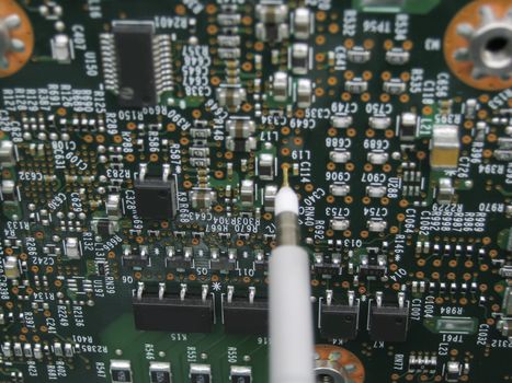 Multimeter probes examining a PCB circuit board