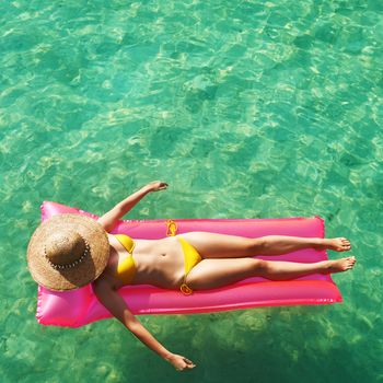 Woman relaxing on inflatable mattress at the beach