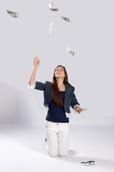 Young long-haired woman kneeling on the floor and throws dollars up to