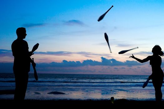 Unidentified people juggling on the ocean beach at sunset. Bali, Indonesi