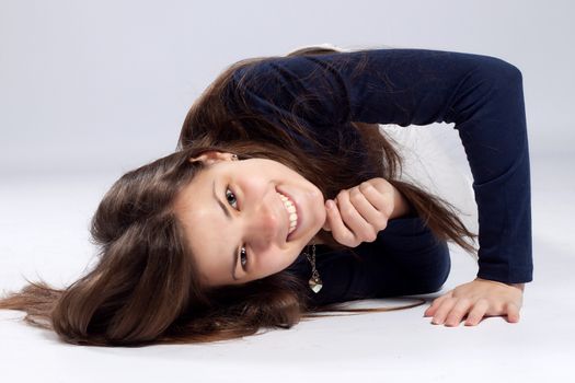 Young long-haired woman without makeup in white jeans and a blue shirt lying on the floor