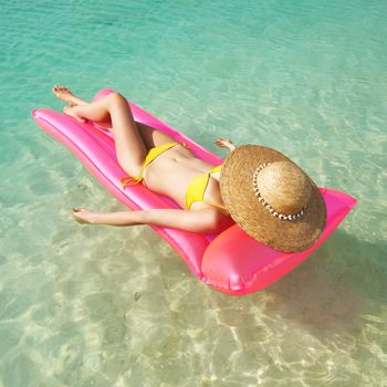 Woman relaxing on inflatable mattress at the beach