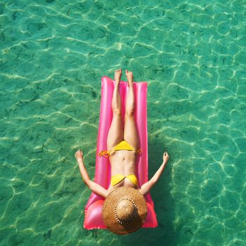 Woman relaxing on inflatable mattress at the beach