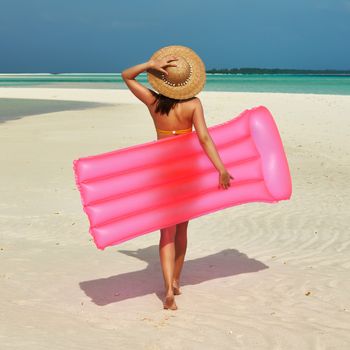 Woman with pink inflatable raft walking at the beach